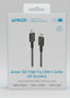 A hand holding a boxed Anker 322 USB-C to USB-C cable in a retail store setting. The white box shows the Anker brand name, product details, and compatibility text, with other packaged goods blurred in the background.