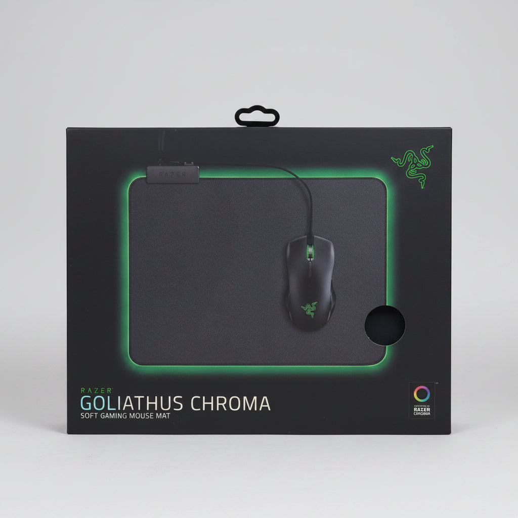 A boxed Razer Goliathus Chroma gaming mouse pad and mouse displayed on a black rolling stand inside a retail store. The box shows a dark mouse pad with green lighting and a black gaming mouse, with Razer branding visible. الصورة الرئيسية