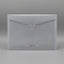A light blue-gray translucent mesh mailer envelope with a diagonal flap, placed on a light wood grain surface.