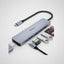 A silver and black USB-C hub with multiple ports, shown with various accessories including a USB-C cable, SD card, and USB flash drive on a white background.