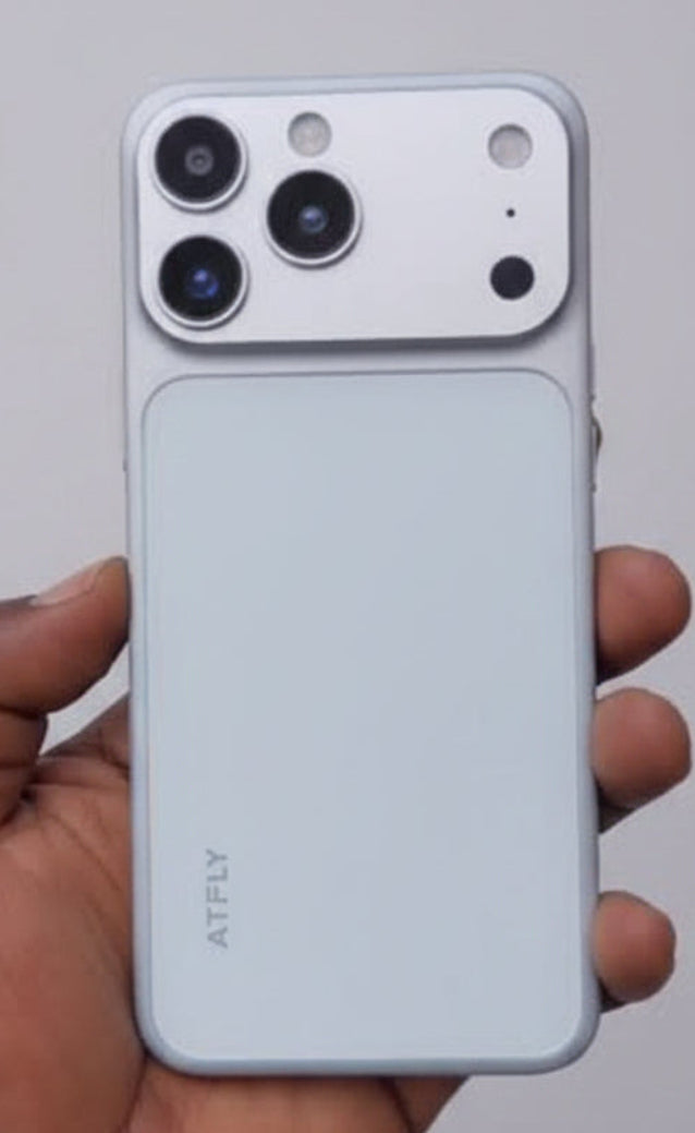 A hand holding a white ATELY smartphone, showing its back panel with a large triple-camera cutout and a matte finish, set against a blurred background.