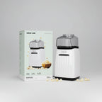 A compact popcorn maker shown next to its retail box on a plain white background. The machine is white with a clear top and black base, and the packaging displays the brand name Green Lion and the model name Poploy.