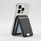 A black textured leather card holder wallet case with a silver metal card slot, shown attached to a silver smartphone on a white background.